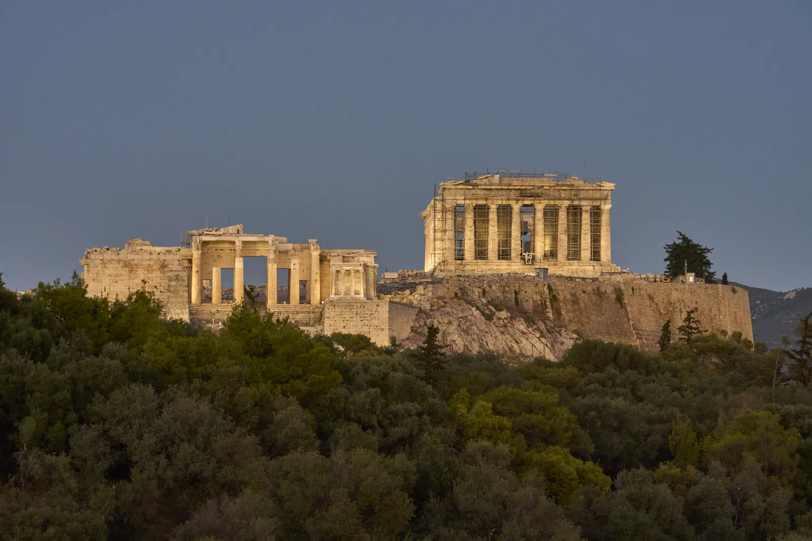 The floodlit Parthenon and Acropolis of Athens glowing at dusk above the city