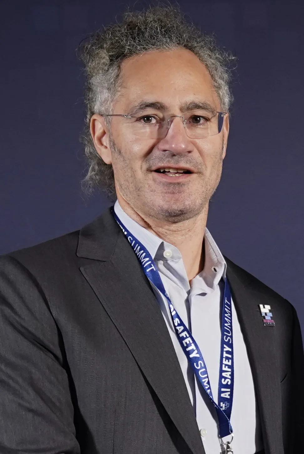 Alex Karp in a dark suit and summit lanyard at Bletchley Park