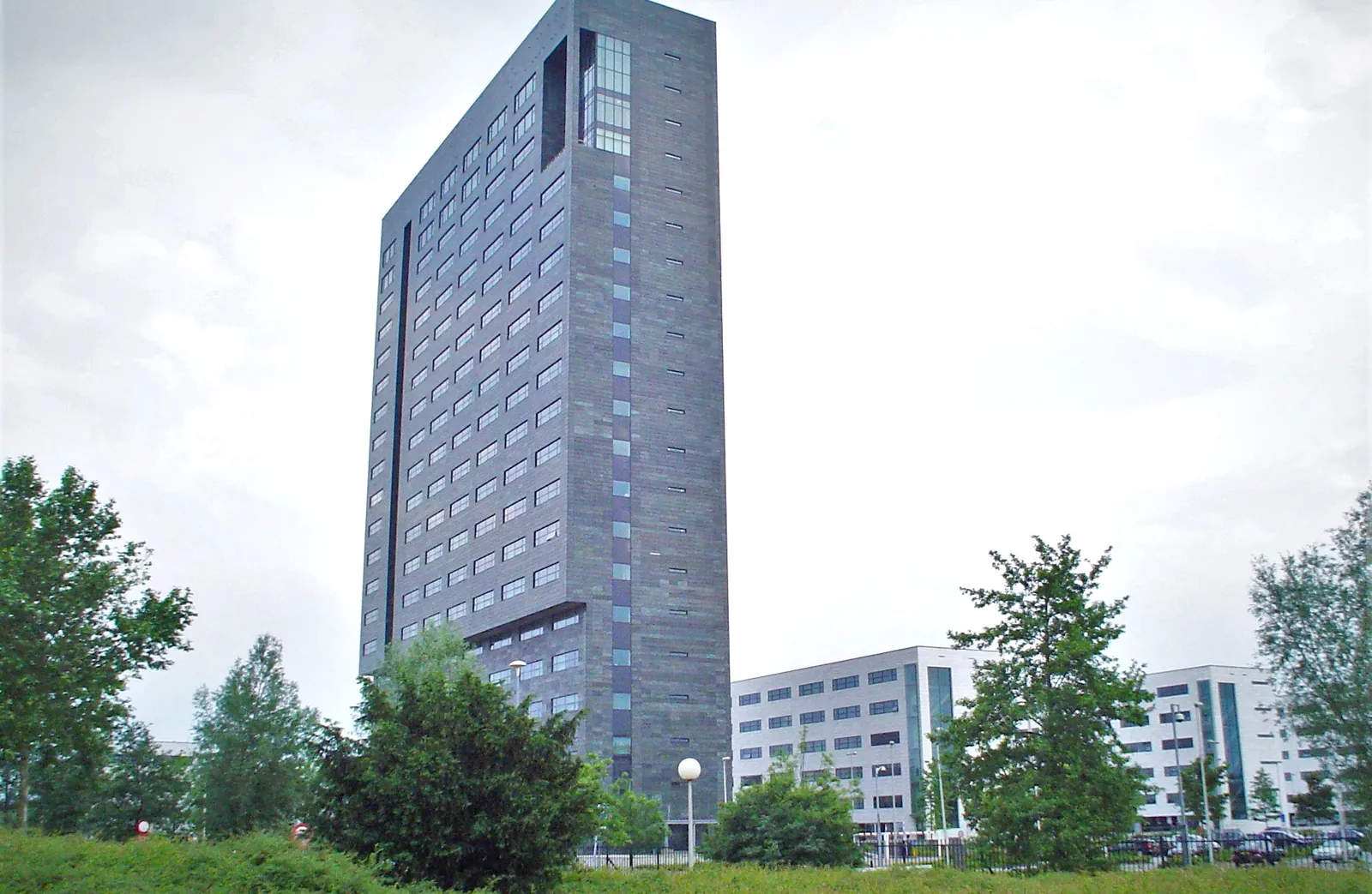 ASML's headquarters tower in Veldhoven, Netherlands, rising above surrounding office buildings and trees