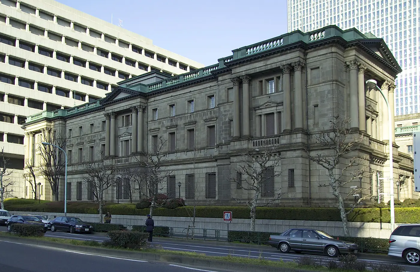 The stone headquarters of the Bank of Japan in Tokyo's Nihonbashi district, with modern skyscrapers rising behind it