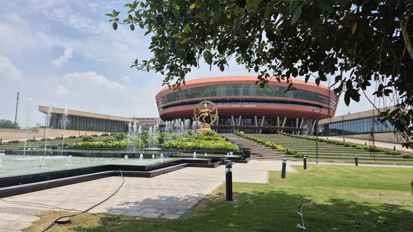 The domed exterior of Bharat Mandapam convention center in New Delhi, seen across a fountain and garden