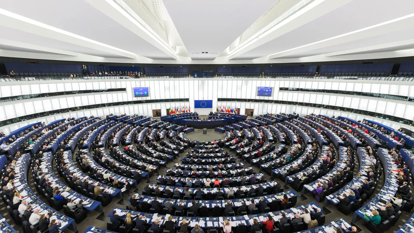 The hemicycle of the European Parliament in Strasbourg, with rows of seats arranged in a semicircle facing the speaker's podium
