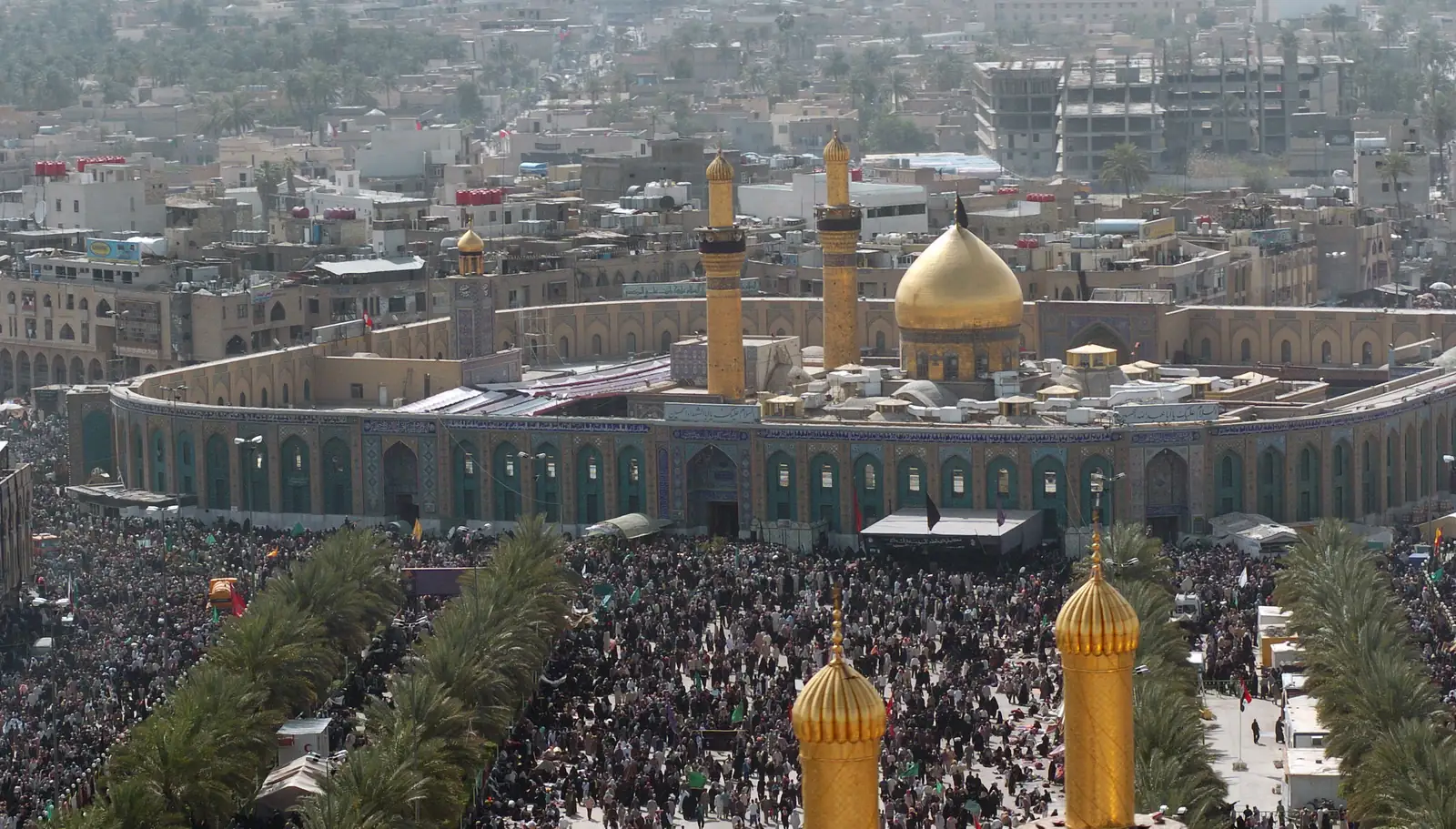 Aerial view of the golden-domed shrine of Hussein in Karbala, surrounded by a dense crowd of pilgrims filling the streets