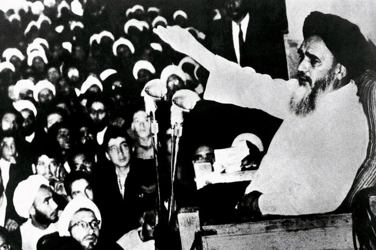 Khomeini speaking to a crowd from behind a microphone at a religious school