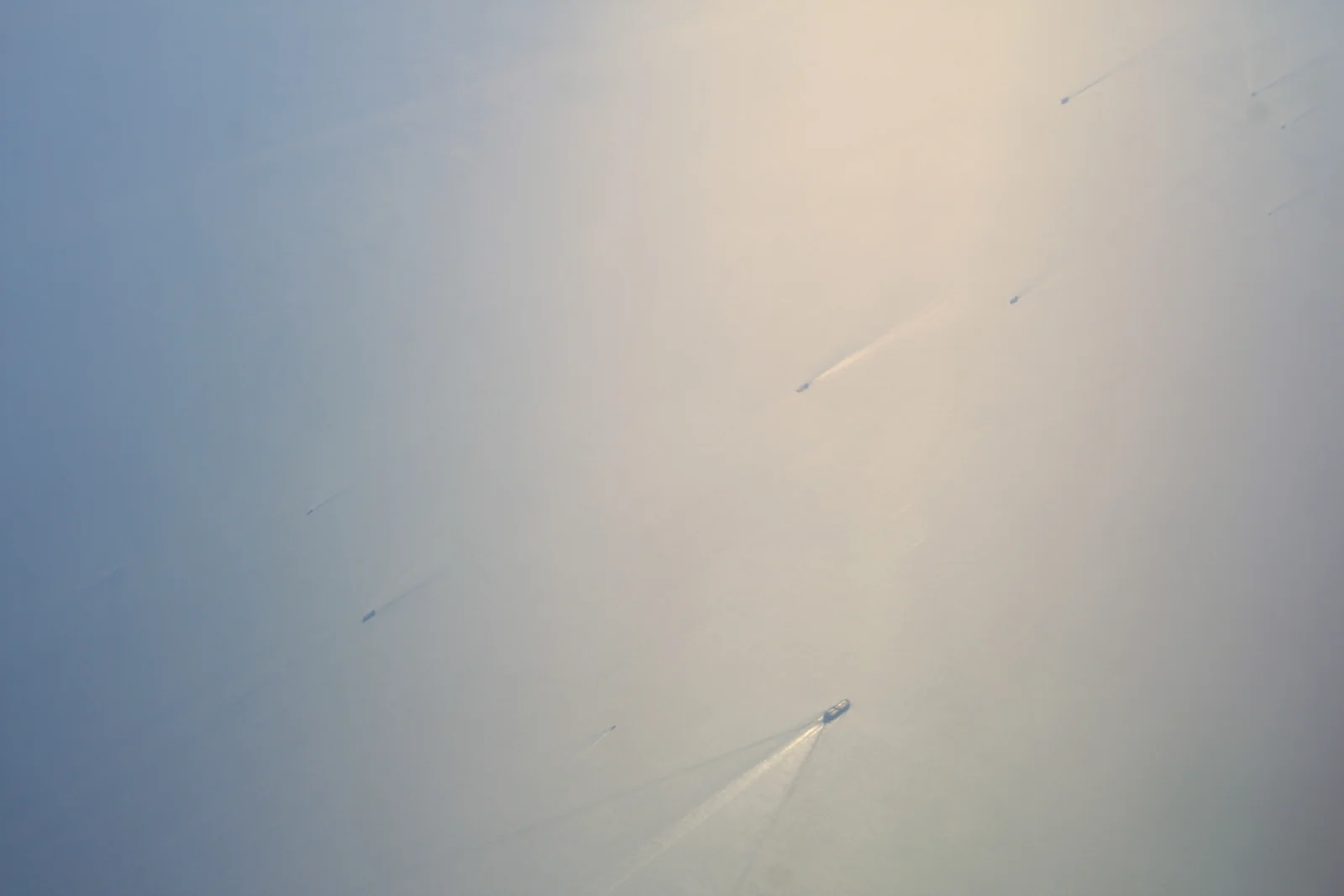 Dozens of cargo ships and tankers scattered across the hazy waters of the Strait of Malacca near Singapore, seen from the air