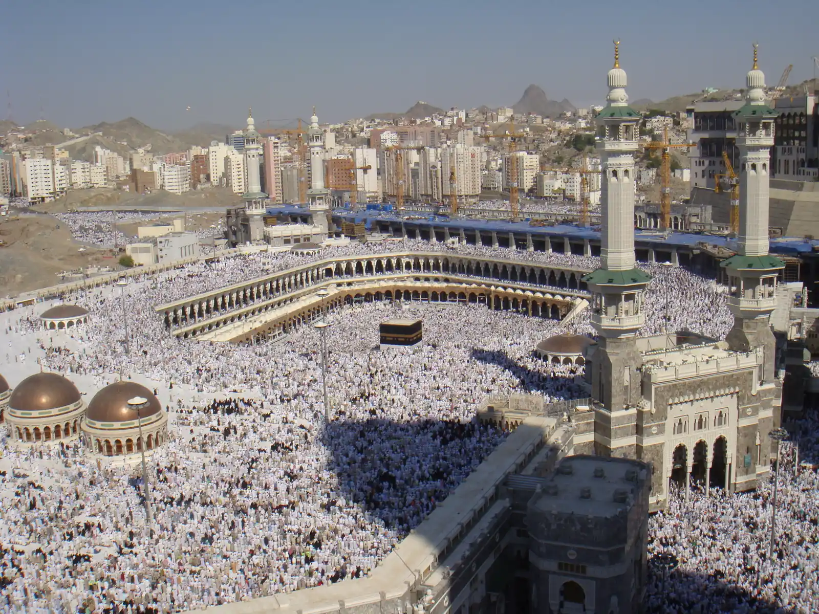 Aerial view of the Grand Mosque in Mecca, with the Kaaba at the center surrounded by dense crowds of pilgrims