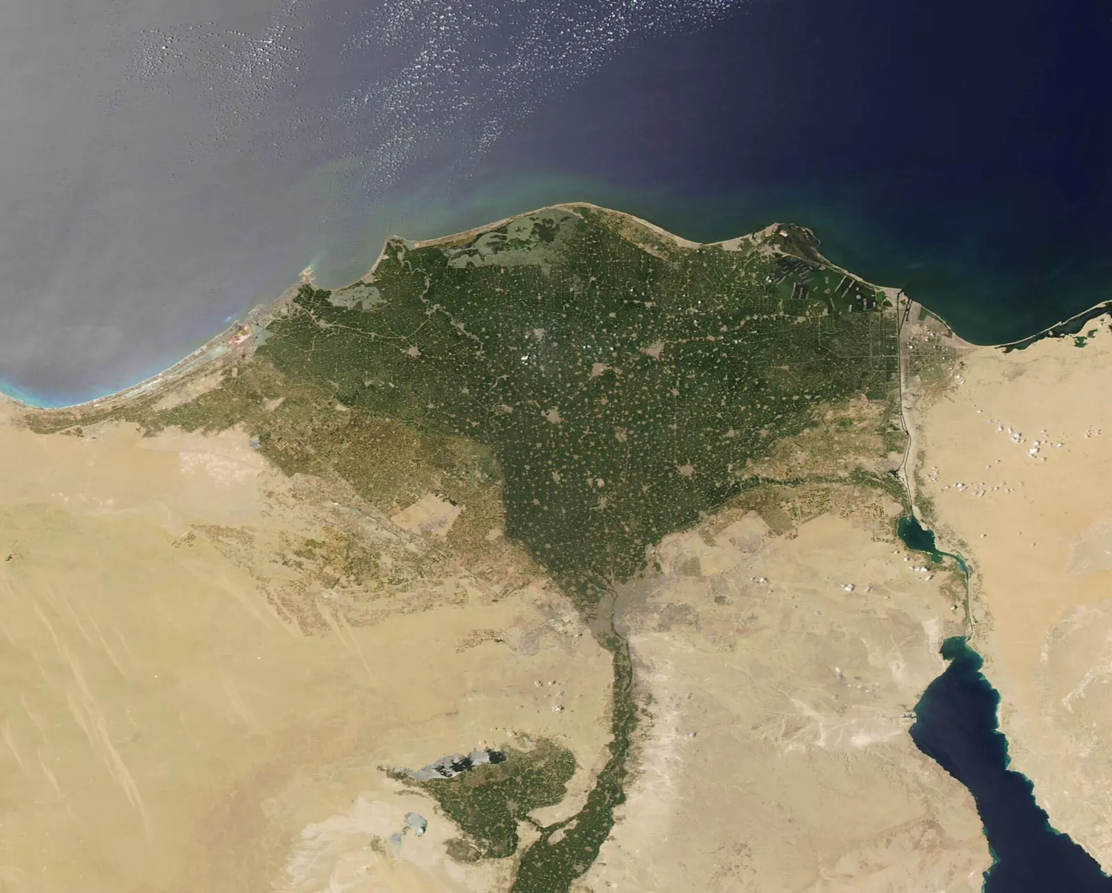 Satellite view of the Nile River Delta from space, showing the green fan of the delta against the tan desert of Egypt, with the Mediterranean Sea at the top