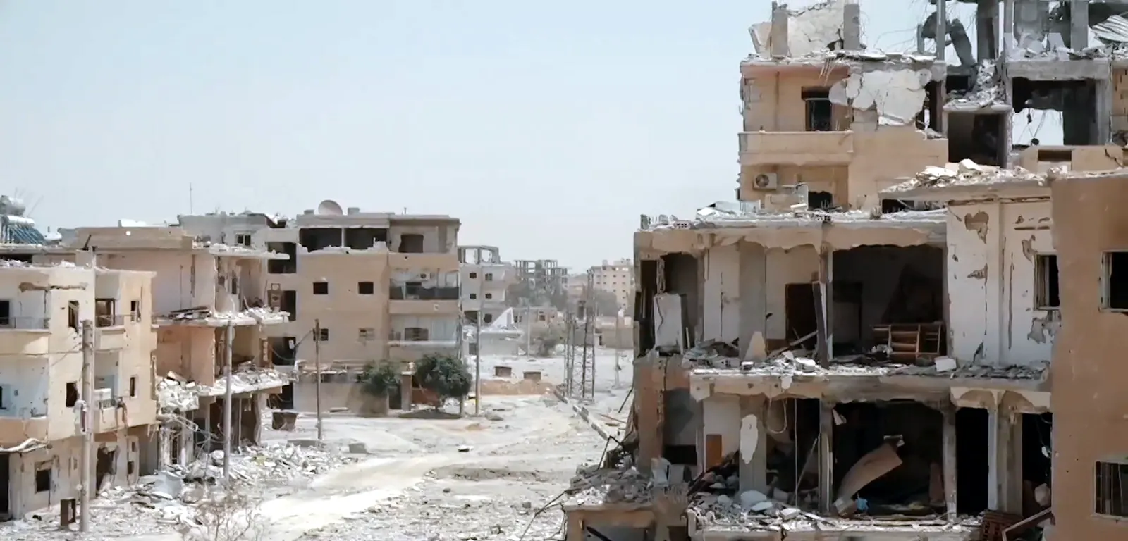 A destroyed neighborhood in Raqqa, Syria, with collapsed buildings and rubble filling the streets