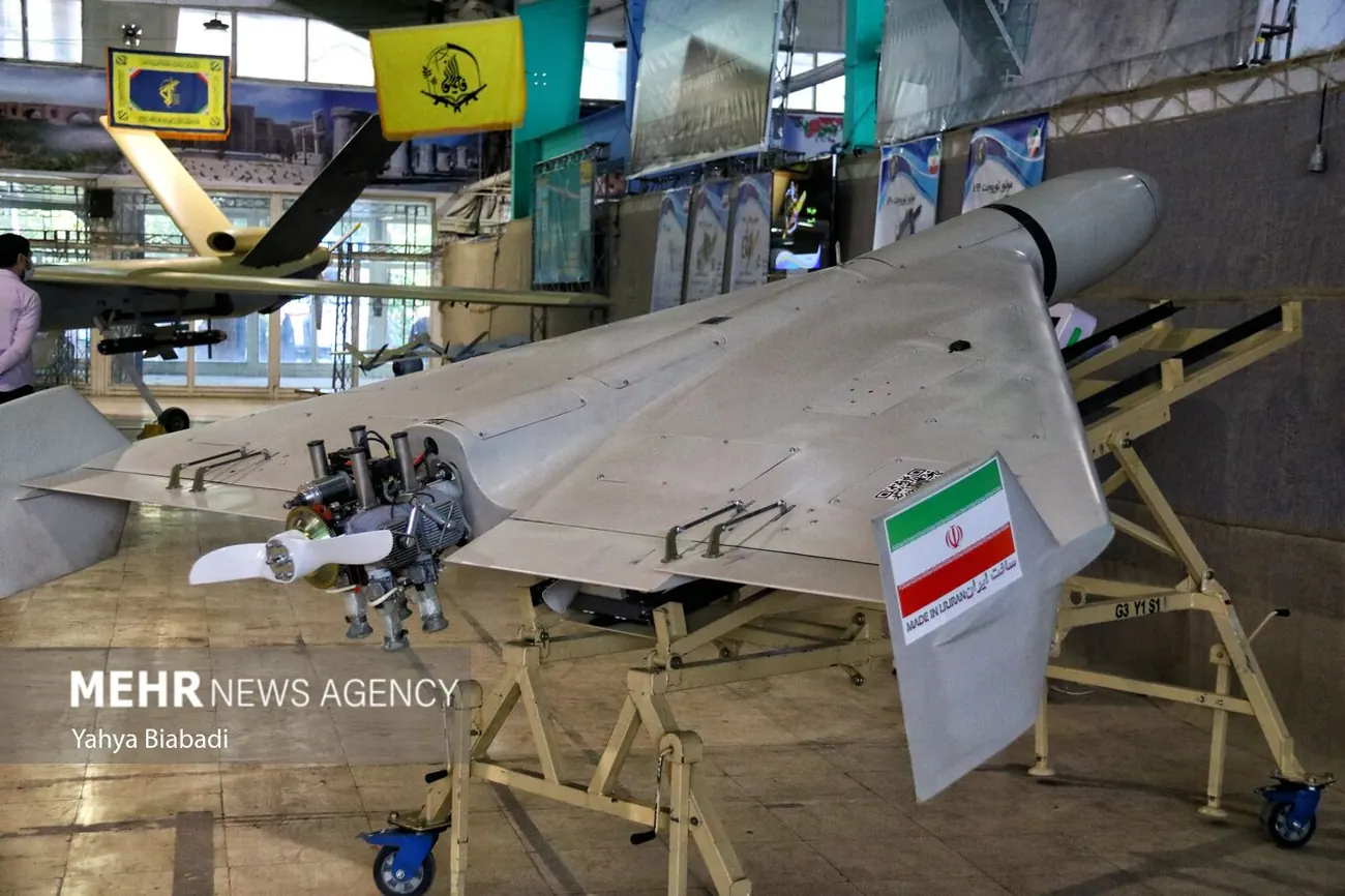 A Shahed-136 attack drone on a launch rail at an IRGC exhibition, with an Iranian flag sticker on its fuselage