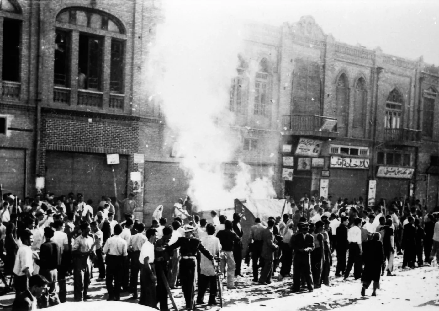 A crowd in a Tehran street burning material taken from a communist newspaper office