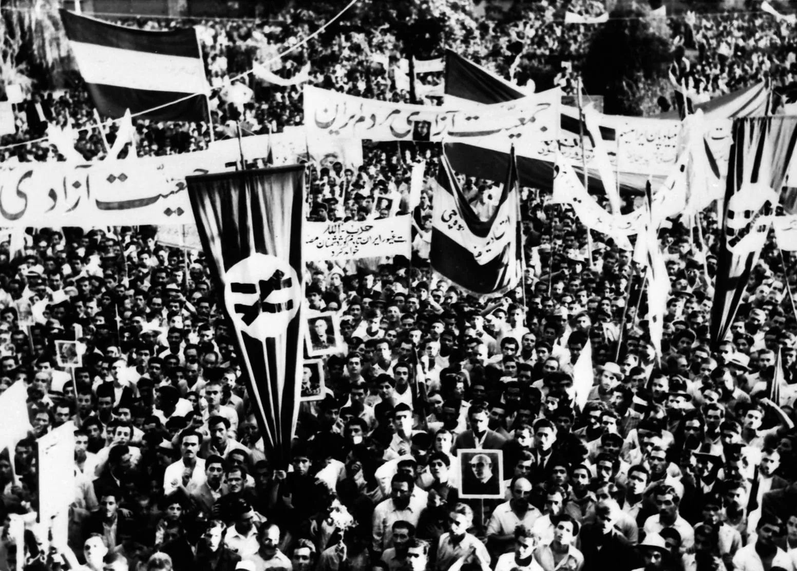 A dense crowd with flags and banners filling a Tehran street during the August 1953 coup