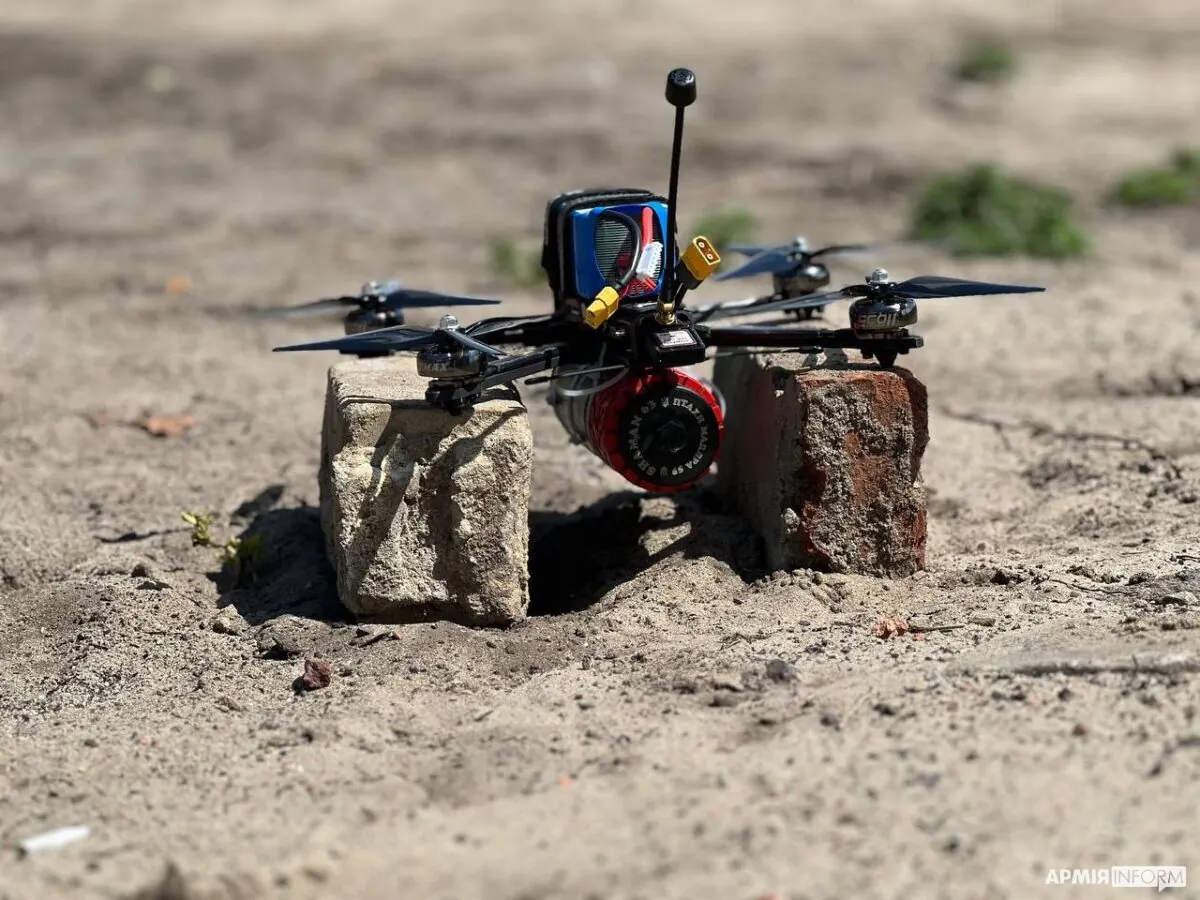A Ukrainian FPV drone fitted with a warhead, resting on bricks on sandy ground