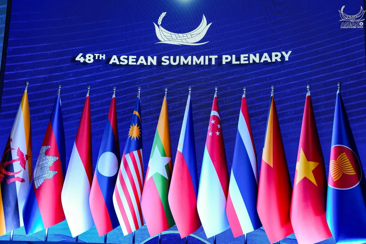 The flags of the 11 ASEAN members and the blue ASEAN flag in a row on a stage, under a screen reading 48th ASEAN Summit Plenary