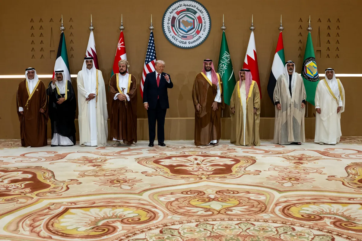Gulf leaders in robes and President Trump in a dark suit stand in a row before the flags of the six GCC members and the United States, under the emblem of the GCC-USA summit