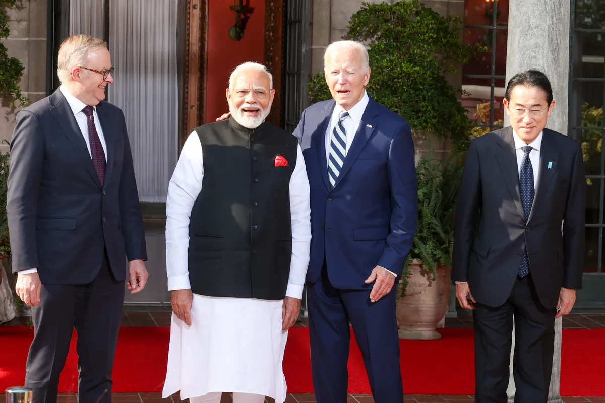 Four leaders stand in a row on a red carpet outside a stone building: Australia's Anthony Albanese, India's Narendra Modi, US President Joe Biden and Japan's Fumio Kishida