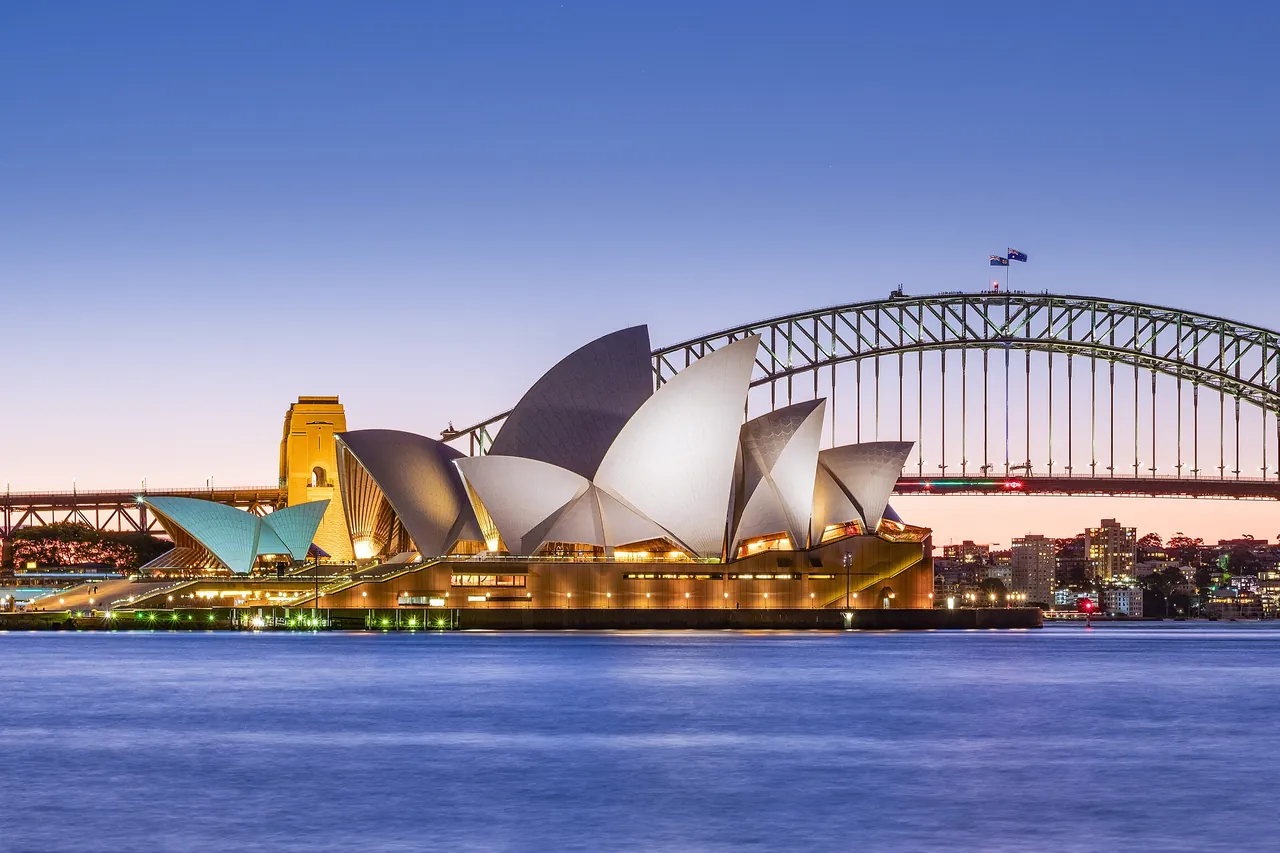 The Sydney Opera House and the Sydney Harbour Bridge at dusk, seen across the harbor
