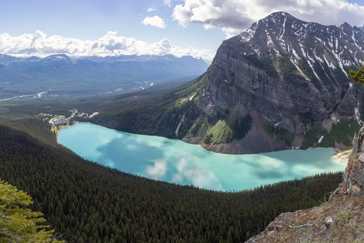 Lake Louise in Banff National Park seen from above, its turquoise water between forest and the cliffs of Mount Fairview