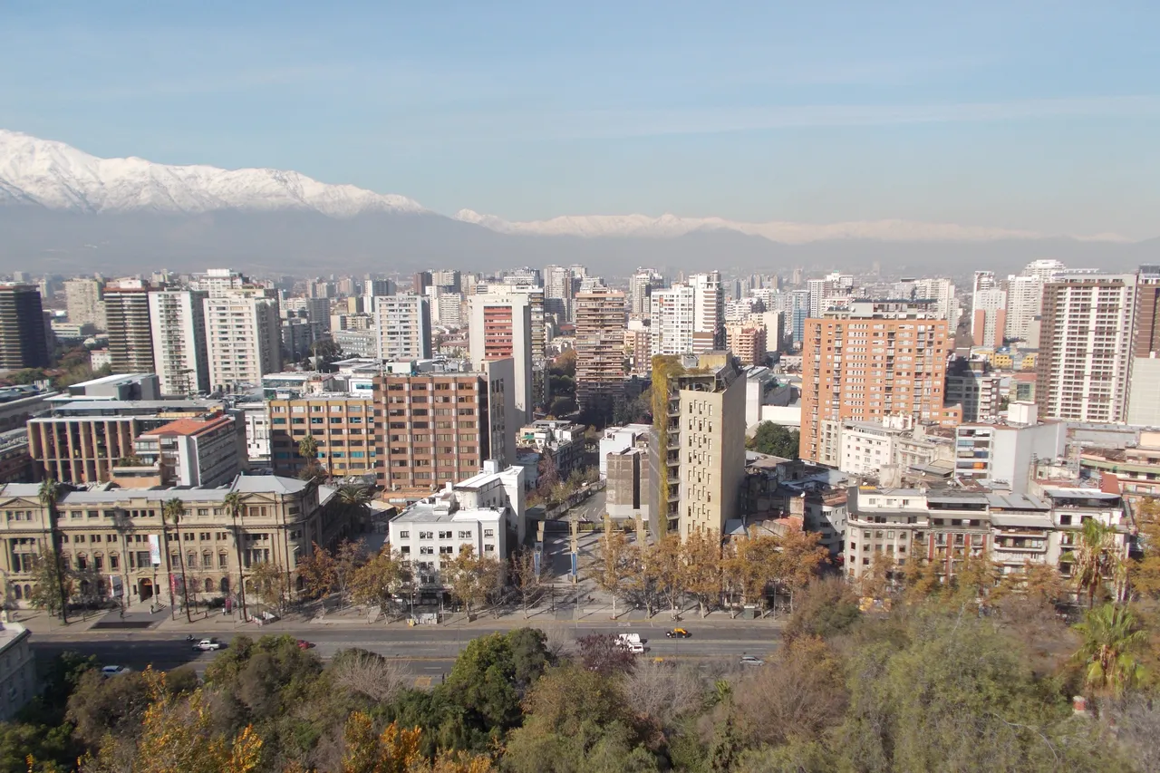 Apartment towers of central Santiago spread toward the snow-covered Andes under a clear sky, seen from Santa Lucía Hill