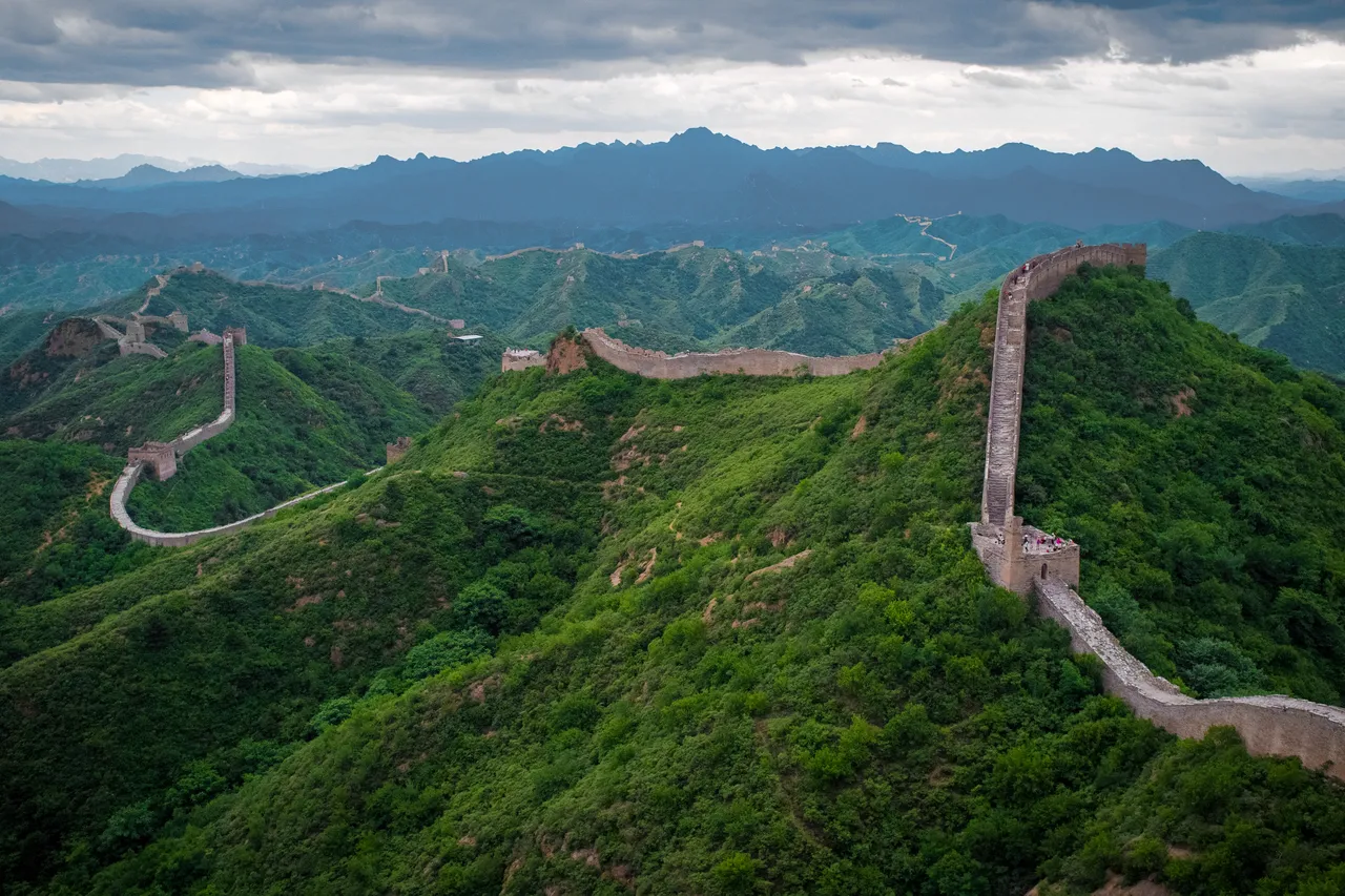 The Great Wall of China winding over green mountain ridges at Jinshanling