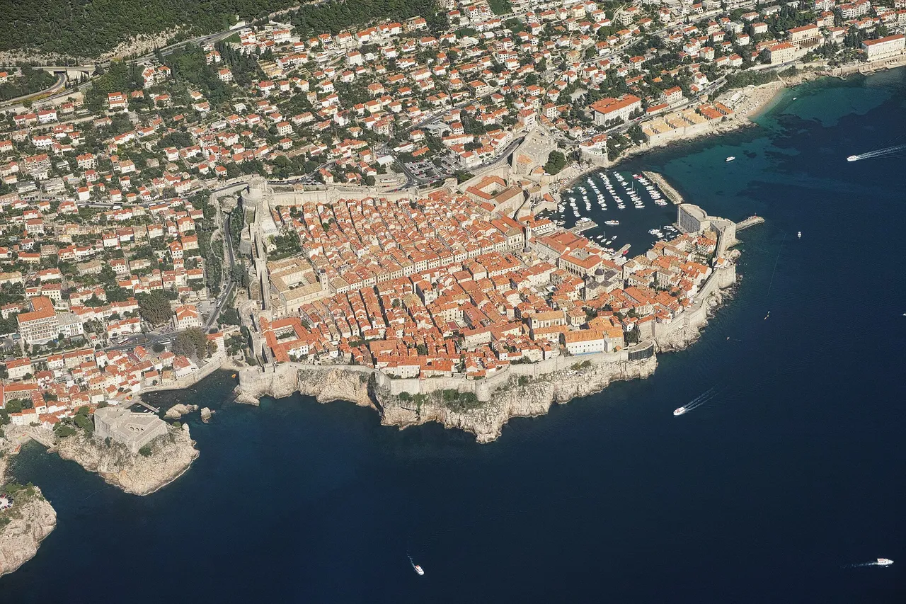 Aerial view of the walled Old Town of Dubrovnik, with red-tiled roofs, the city walls and the old harbour on the blue Adriatic Sea