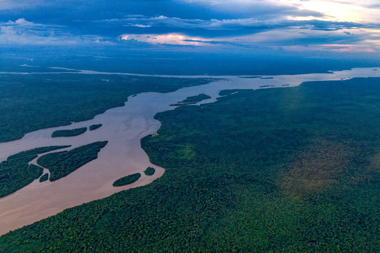 The wide brown Essequibo River winding past islands through unbroken green rainforest, seen from a plane