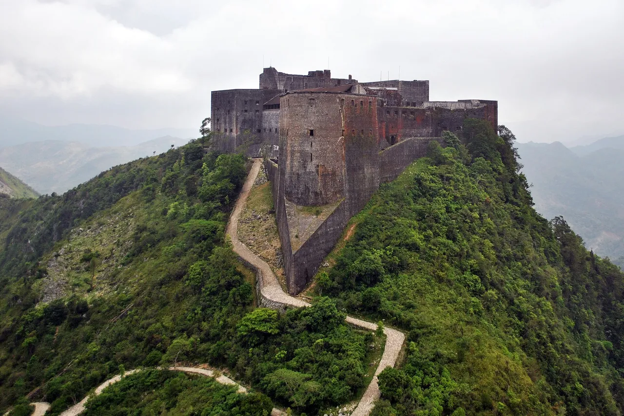 The Citadelle Laferrière, a huge stone fortress, on top of a green mountain, with a winding path below