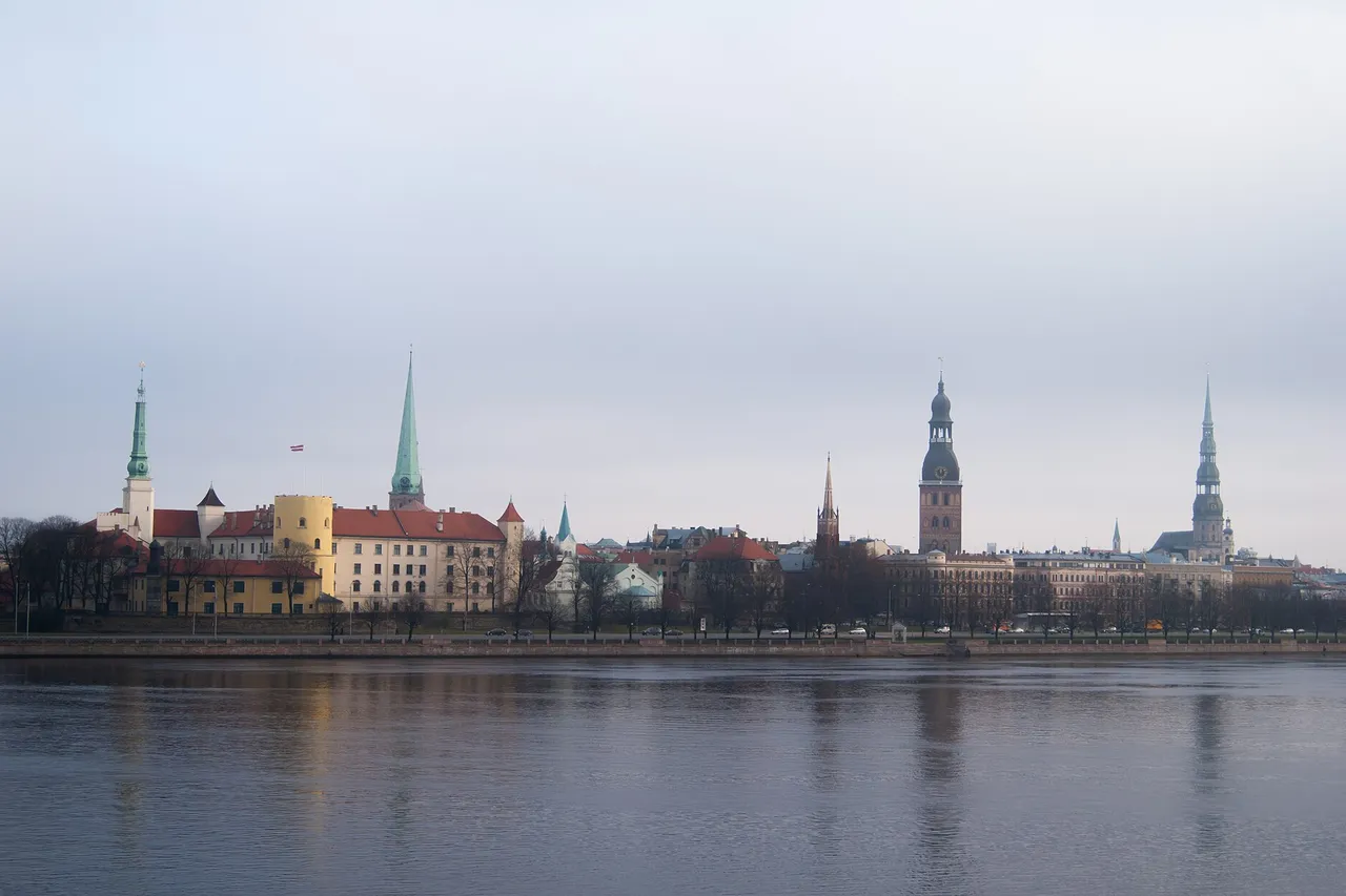 The old town of Riga seen across the wide Daugava River, with the castle, church spires and the cathedral tower on a gray day