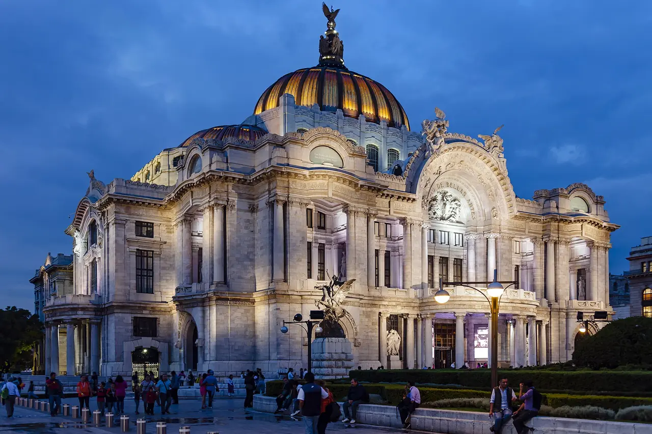 The white marble Palacio de Bellas Artes in Mexico City at dusk, its dome lit gold