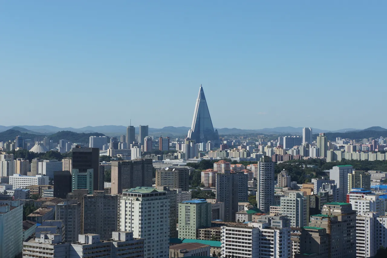 Apartment towers in central Pyongyang under a clear sky, with the pyramid-shaped Ryugyong Hotel rising behind them