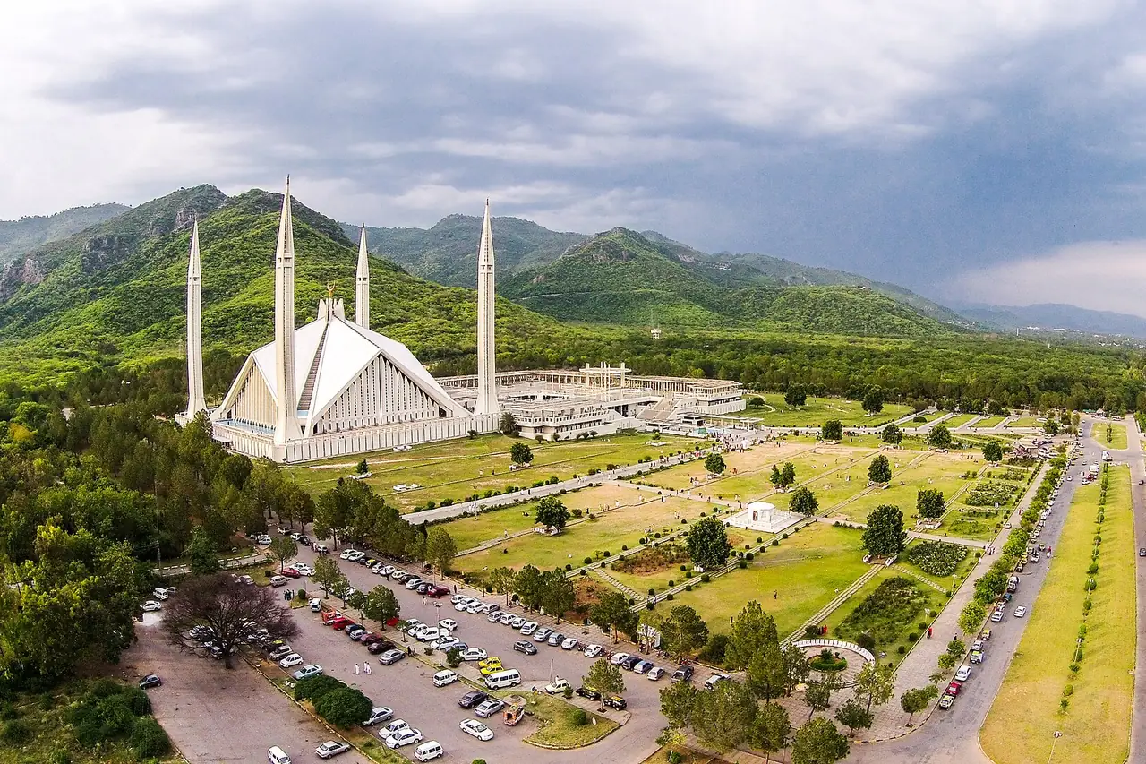 The Faisal Mosque in Islamabad, with its four minarets, below the green Margalla Hills