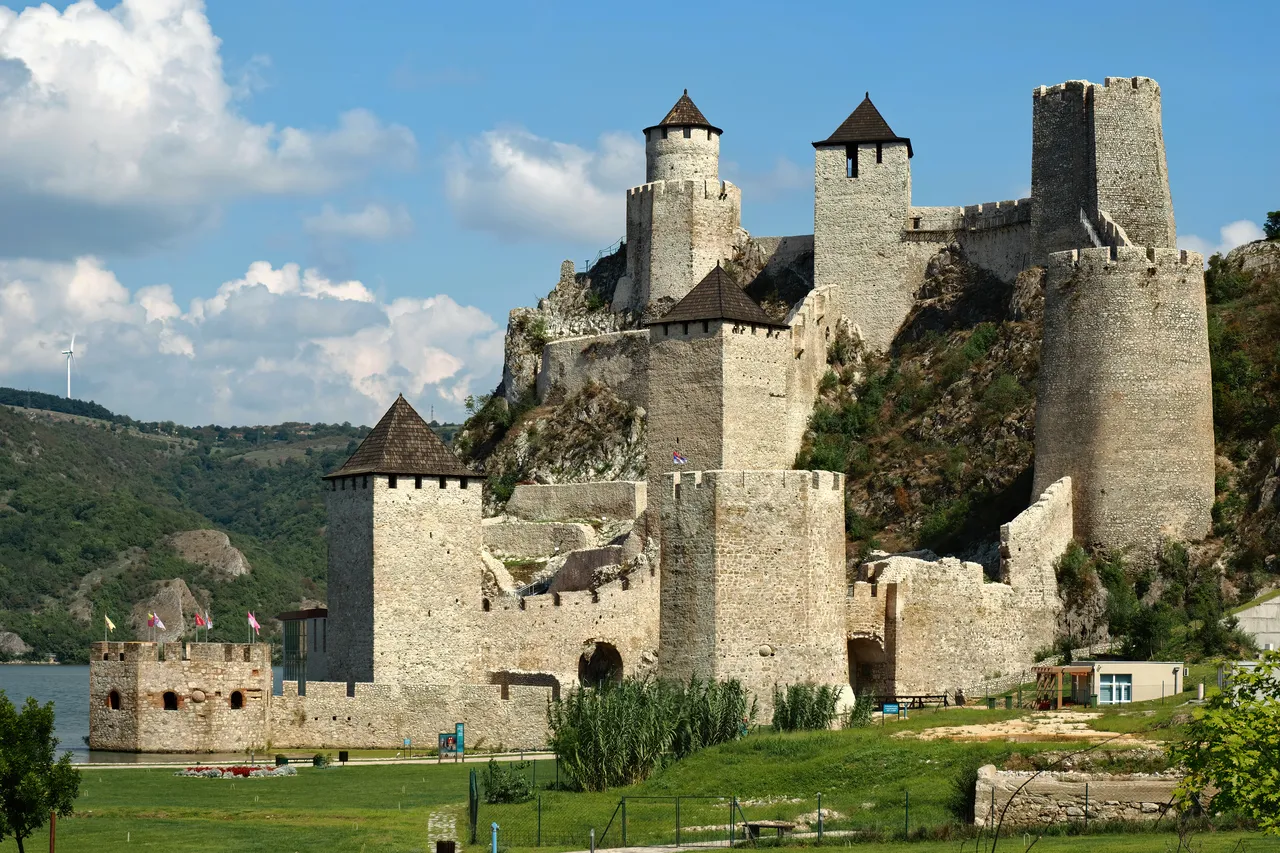 Golubac Fortress, a medieval stone castle with tall towers on a green hillside above the Danube River