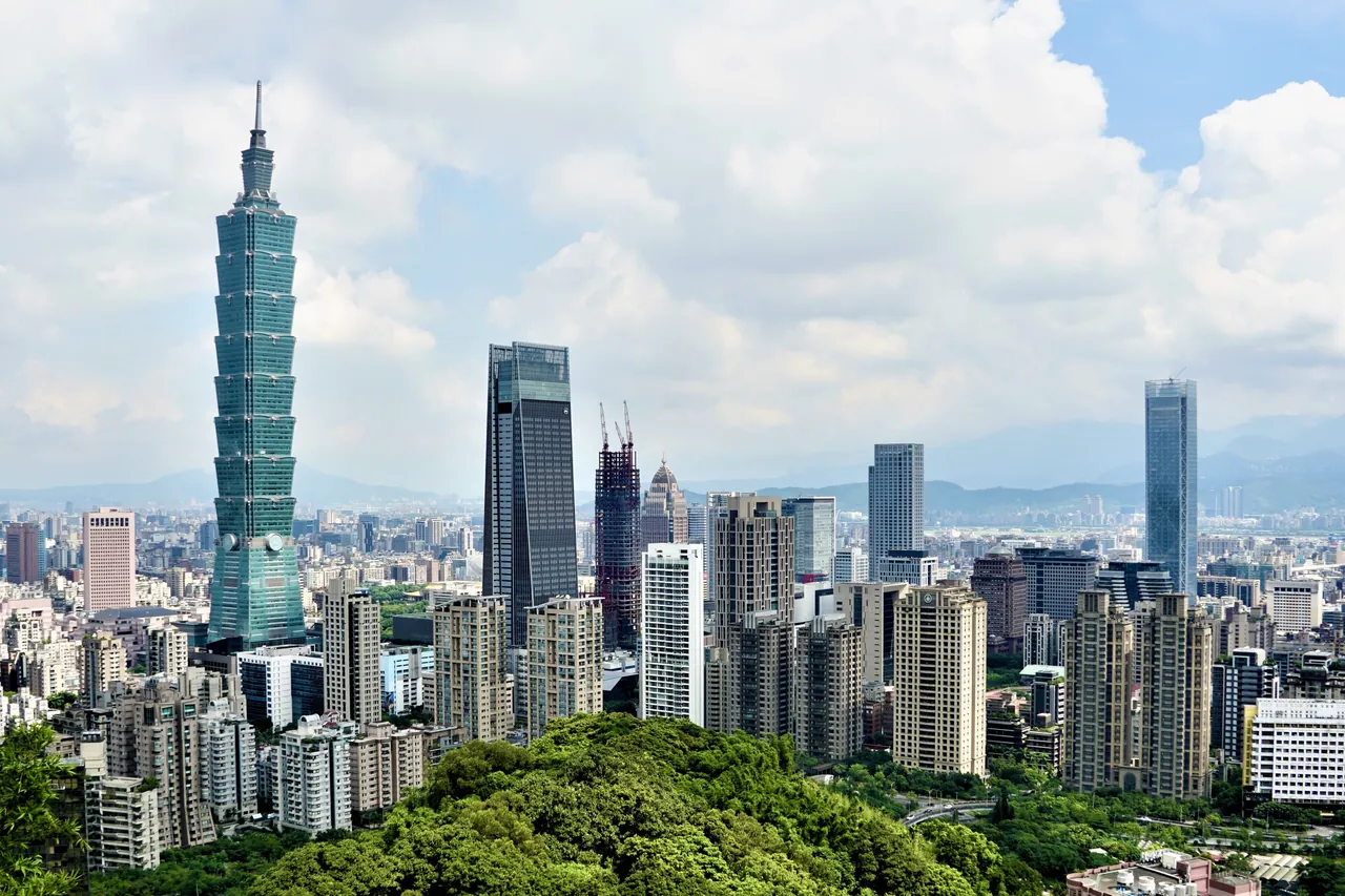 Taipei 101 and the Xinyi district skyline seen from Elephant Mountain, with green hills in front