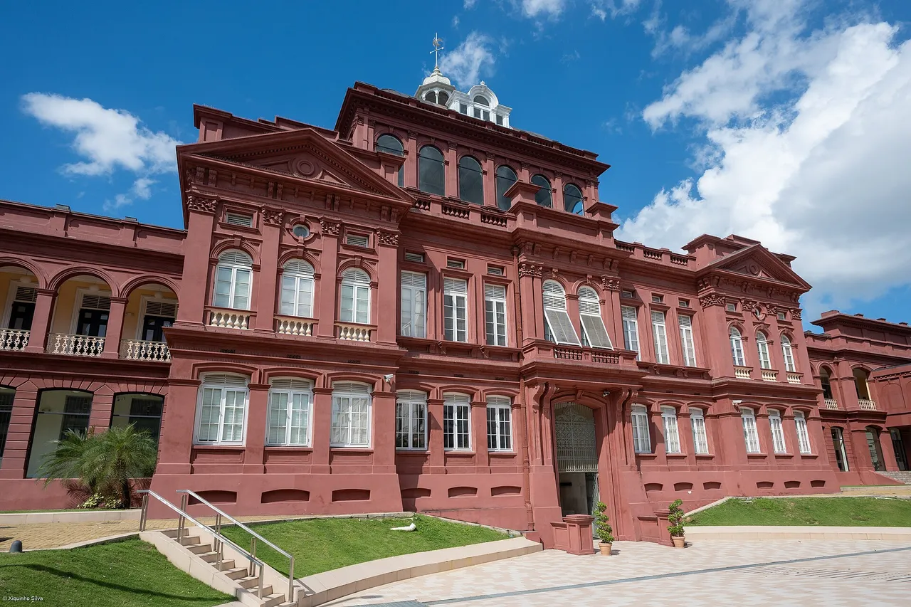 The Red House in Port of Spain, a large red-painted building with white window frames, arches and a small dome, under a blue sky