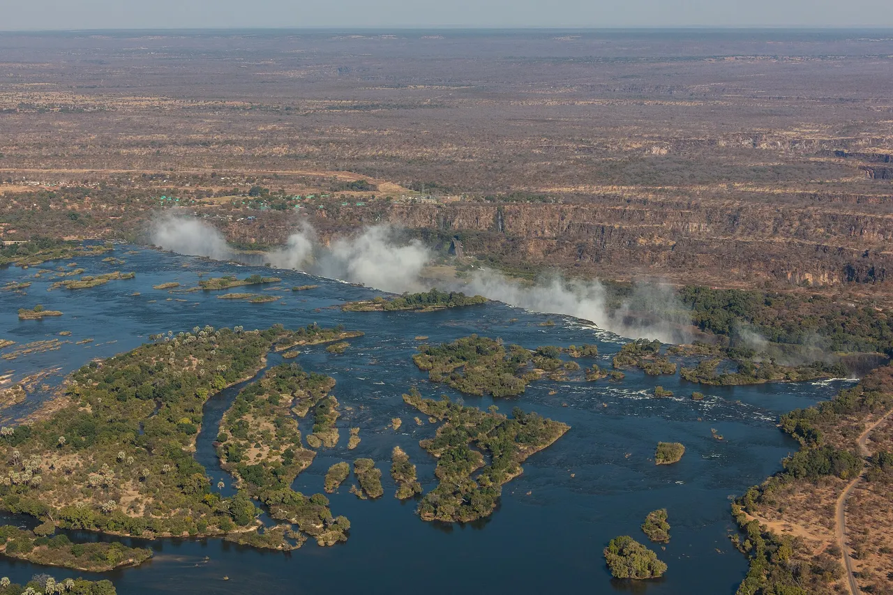 Aerial view of Victoria Falls, with spray rising from the gorge and the wide Zambezi River full of green islands in front