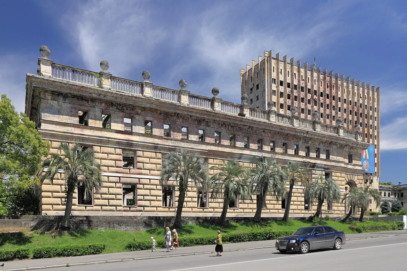 The burned-out shell of a large stone government building in Sukhumi, with palm trees in front