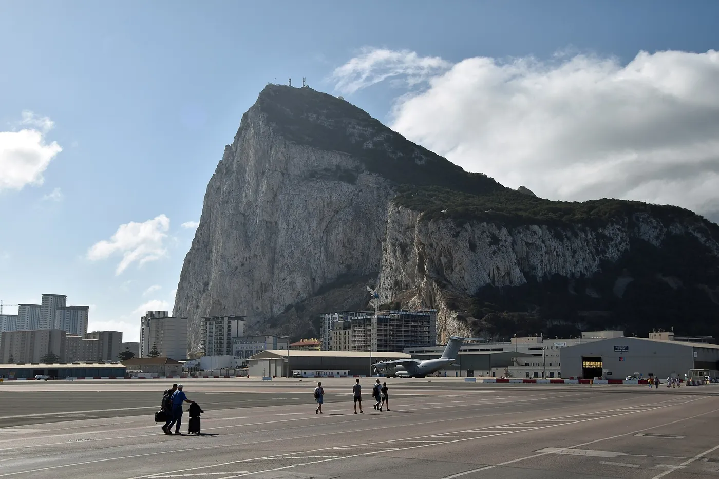 People walking across Gibraltar's airport runway toward the Rock of Gibraltar